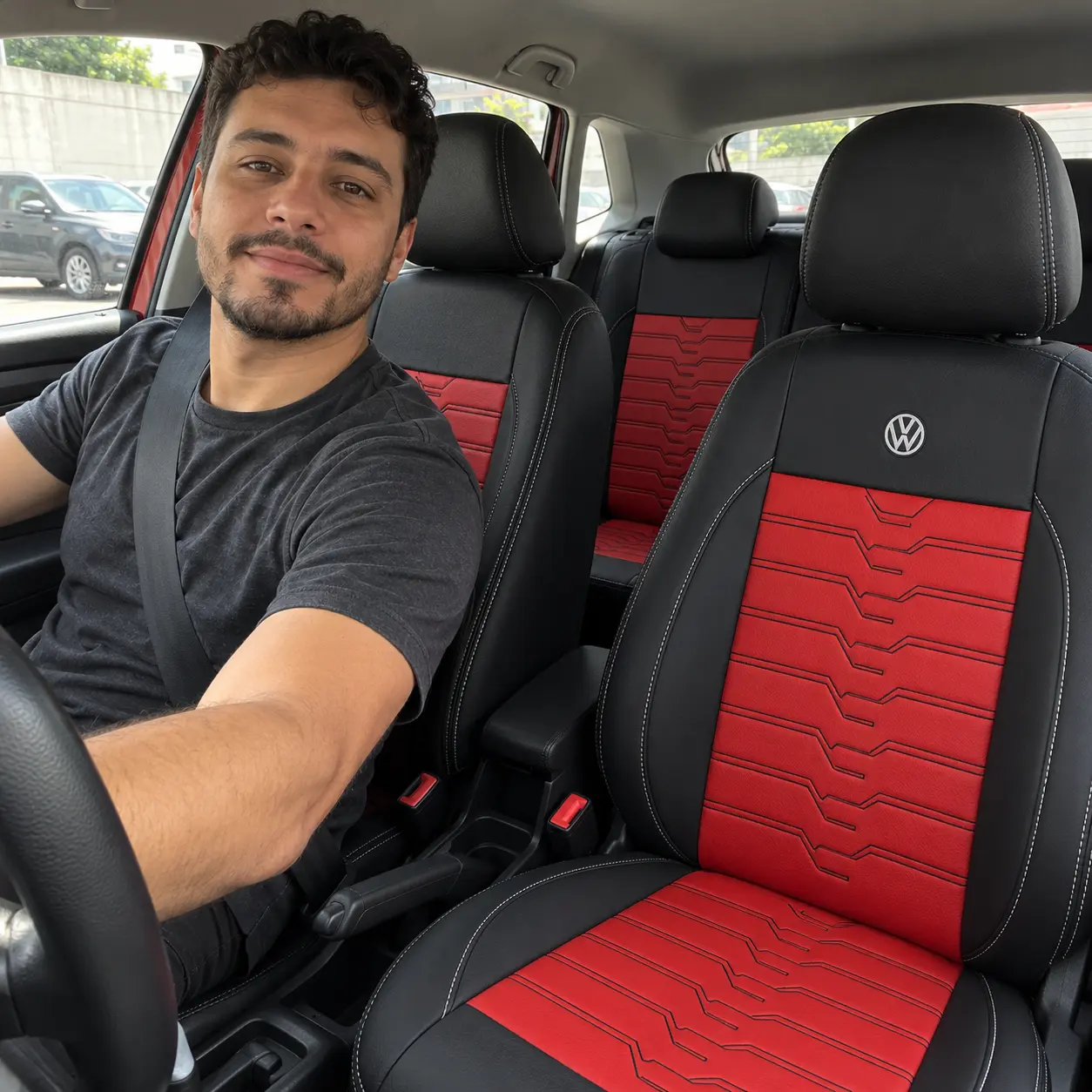 Cliente de camiseta escura ao volante do Volkswagen Polo com capas pretas com detalhes vermelhos e logo Volkswagen bordada