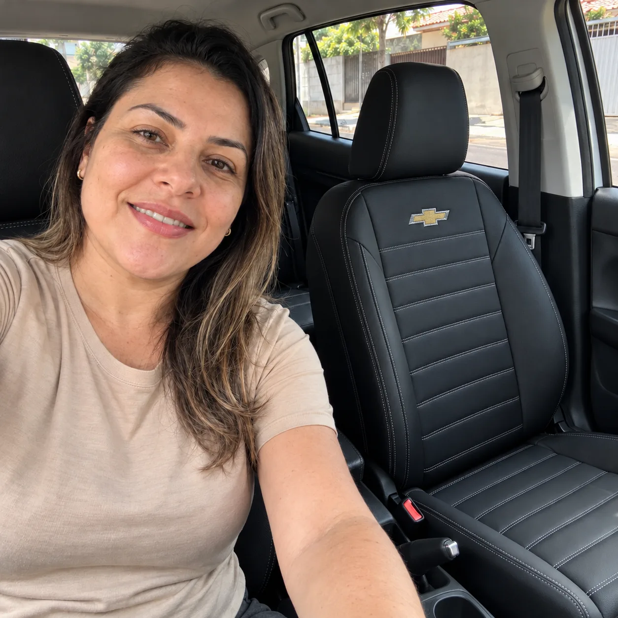 Mariana no carro ao lado do banco dianteiro com capa preta, costura Clássico branca e logo Chevrolet bordada